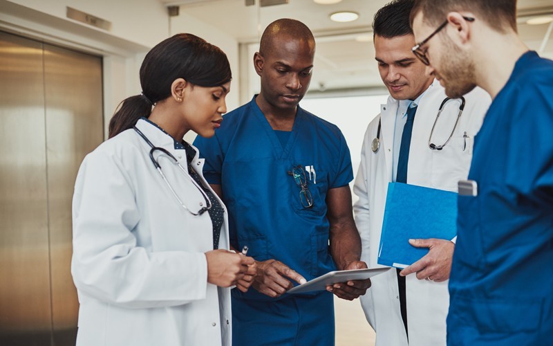 For healtchcare a group of health professional discussing something and using an apple device