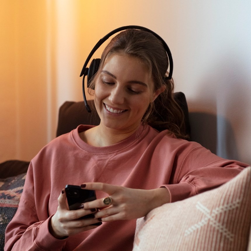 ADAPT 260 woman with headset on looking at mobile phone at home