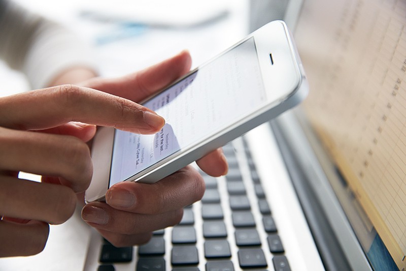 F5 Networks help you enable fast, available and secure applications Close up of a business professional using a smart phone while also on laptop computer