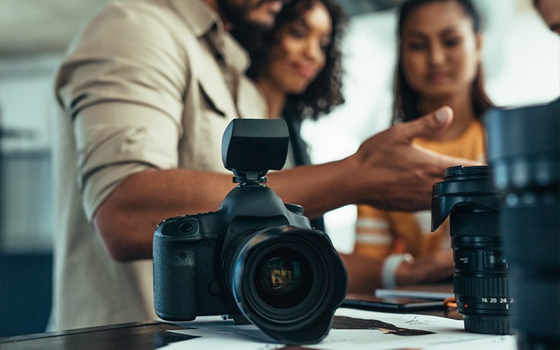 Group of people chatting next to a DSLR camera