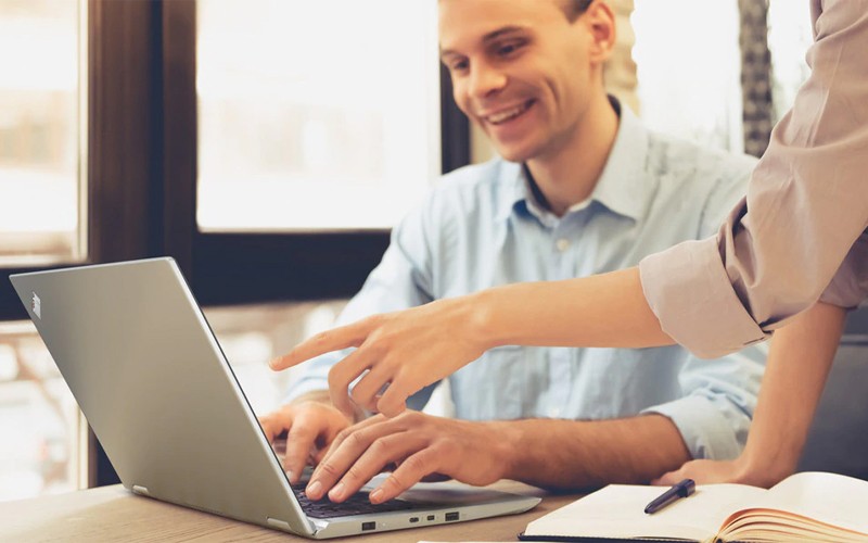 A device for every workload Man using a Lenovo laptop with a colleague