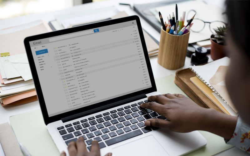 Woman using laptop with email inbox displayed