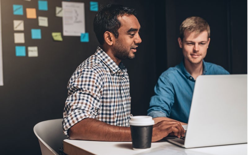 Centralise cloud storage with NetApp Two men talking while looking at laptop