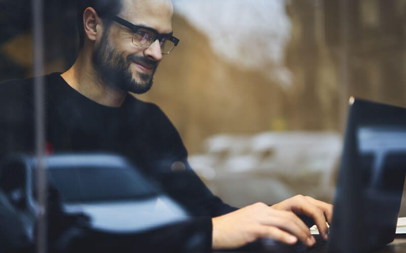 business-man-working-remoteley-smiling-at-laptop