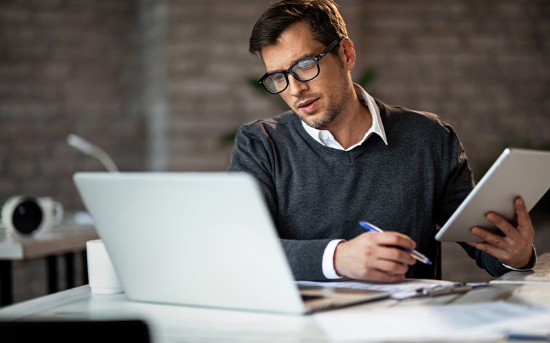Optimise User Experience Every Step of Your Migration Man holding a tablet while looking at a laptop