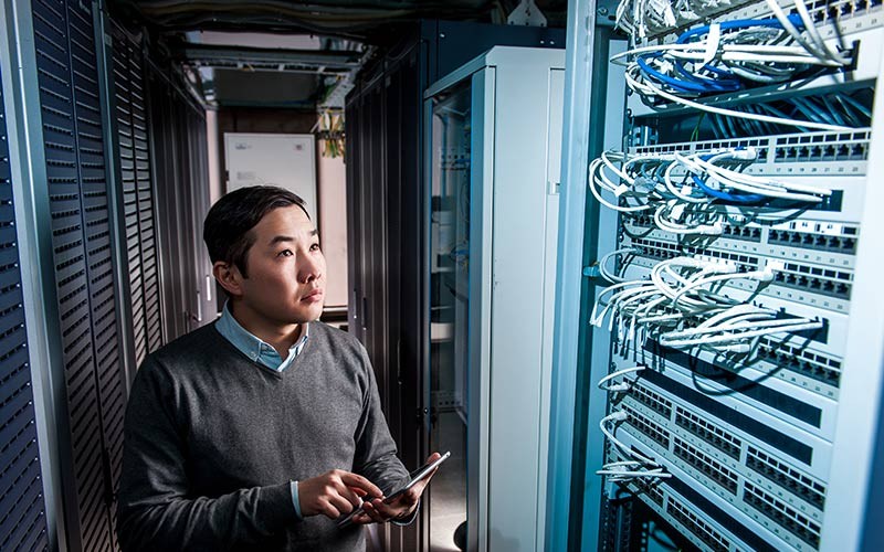 A reliable network backbone Man in a server room sorting out networking cables.